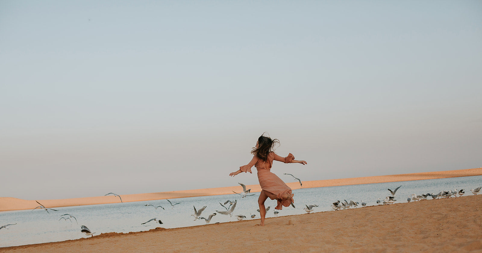 Girl chasing birds on the beach 